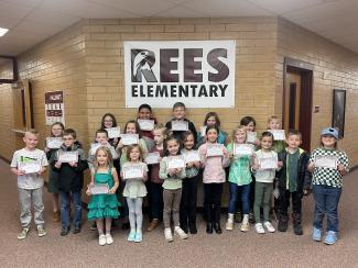 Rees boys and girls holding their student of the month certificates. 