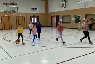 Six girls running down the court in the basketball tournament